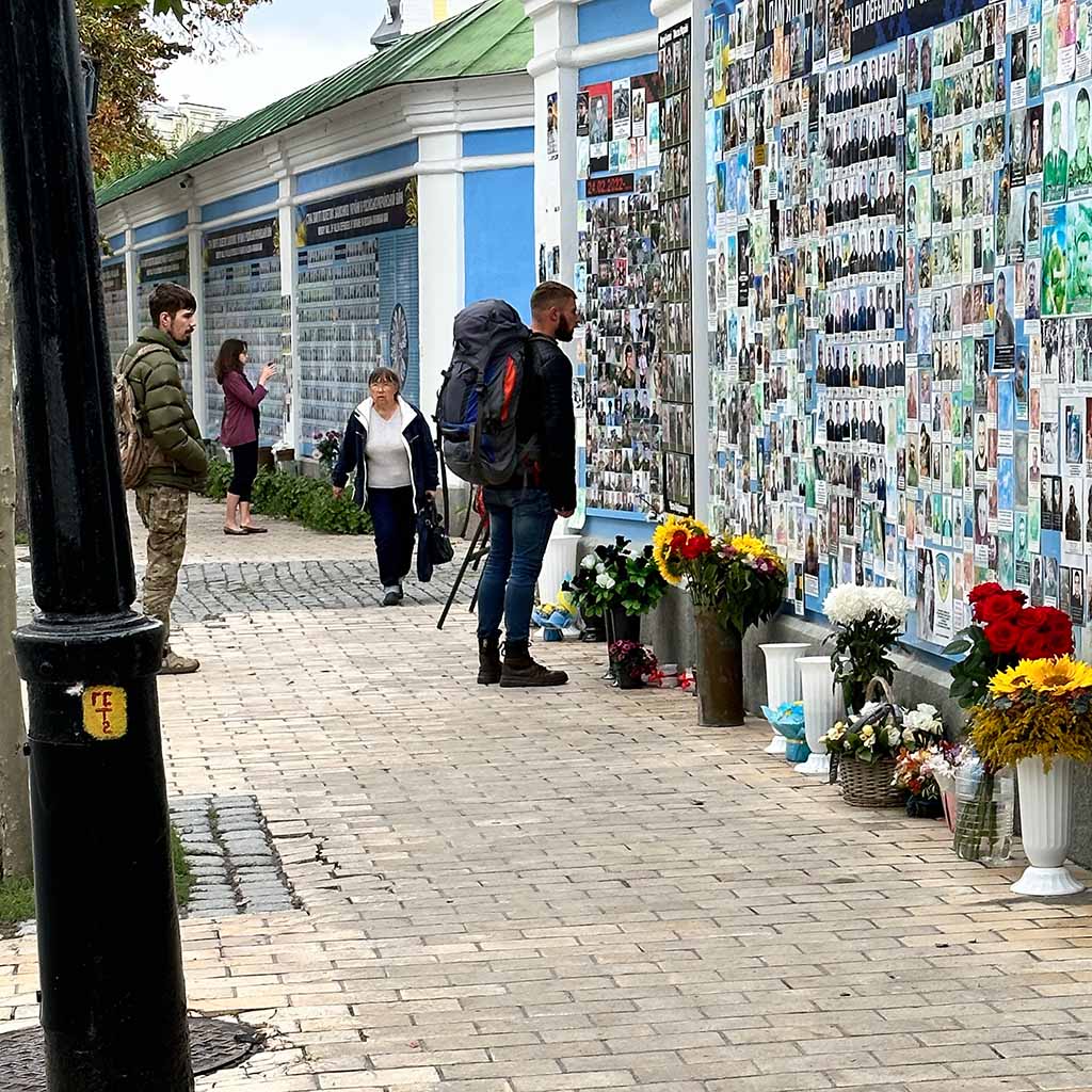 Transparente der Gefallenen von Mariupol. Bilder mit unzähligen Namen an einer endlos scheinenden „Memorial Wall“, einer Erinnerungswand mit den Getöteten seit 2014. Was fühlt ein junger Mann, der in Unform und Rucksack vor dieser Wand steht und intensiv in die Gesichter der Gefallen schaut?