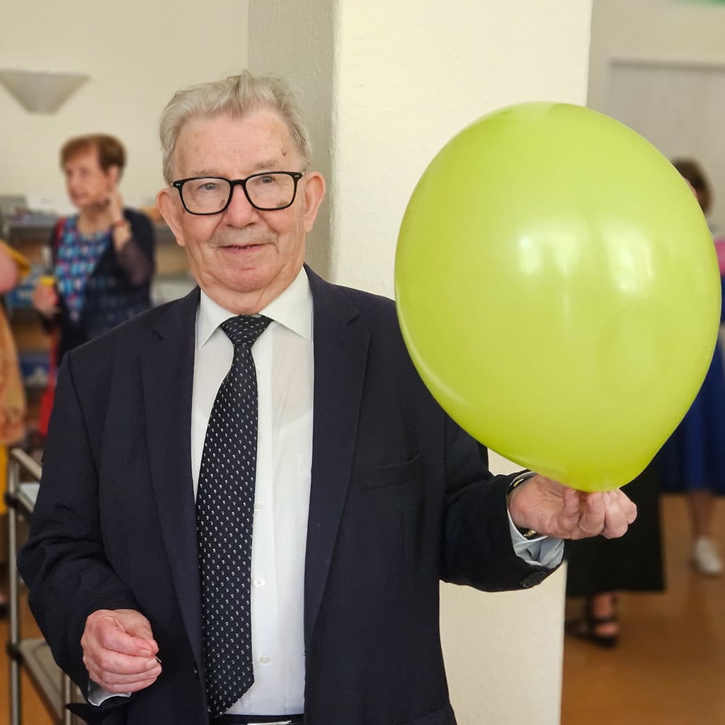 P. Johannes Moosmann mit Luftballon und spitzer Nadel 60 Luftballons platzten als fröhlicher Salut