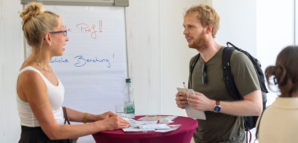Impressionen vom Campus-Day 2026 Foto vom Campus-Day 2026: Eine Frau und ein Mann sprechen an einem Stehtisch miteinander