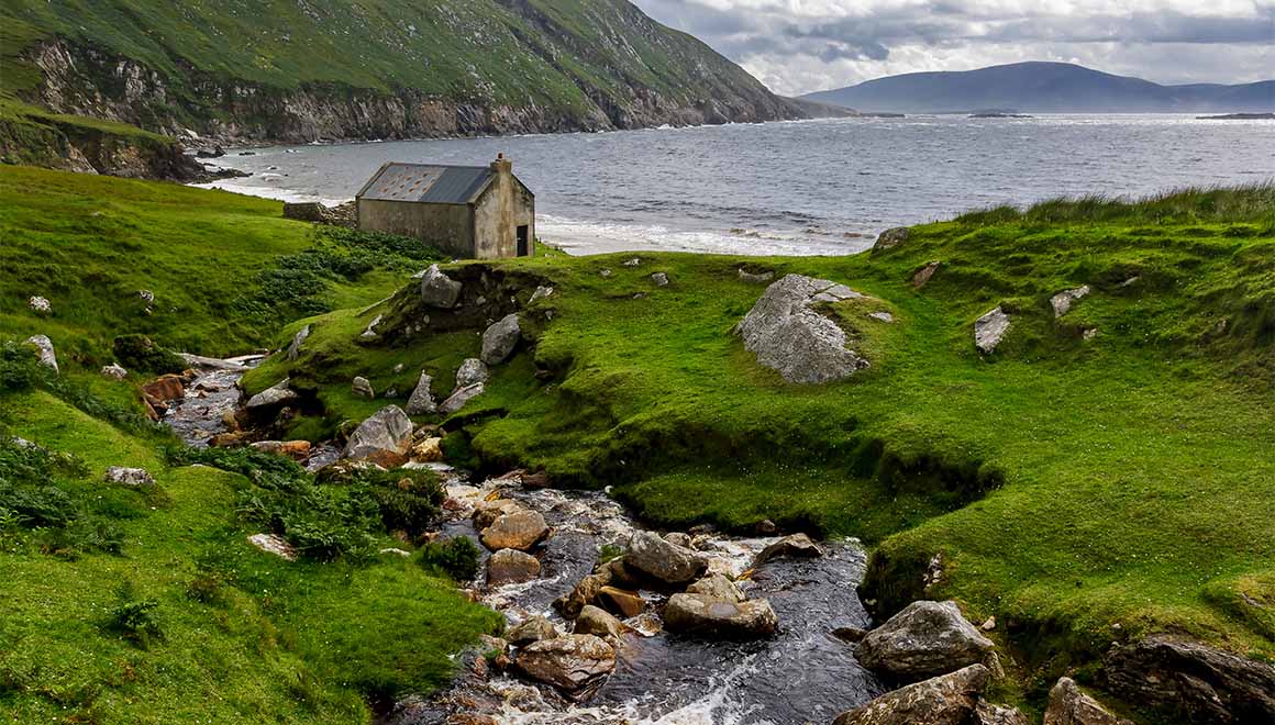 Felsen, Wildbach, Wiesen, Wolken an der Küste von Achill Island in Irland