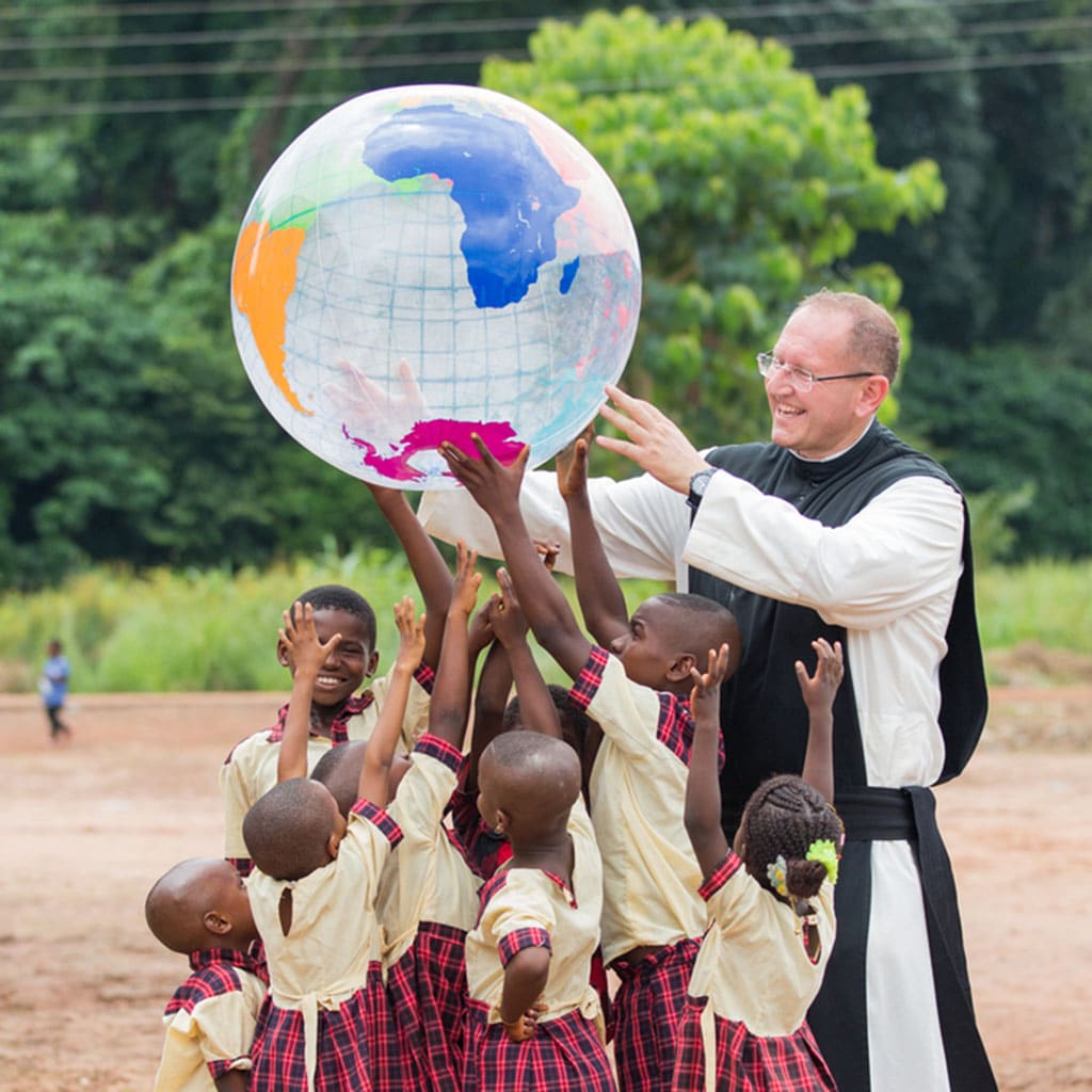 Kinder in Afrika mit Weltkugel und Missio-Nationaldirektor P. Karl Wallner