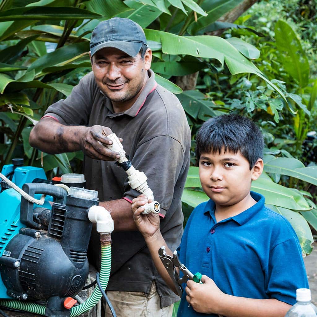 Vater und Sohn in Paraguay bei der gemeinsamen Reparatur eines Elektrogerätes.
